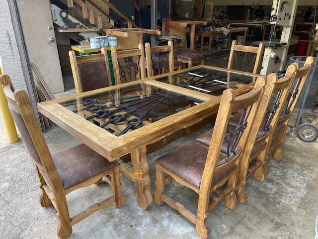 A wooden dining table and chairs are sitting in a wood shop