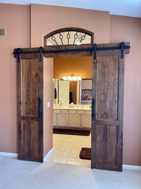 A bedroom with sliding barn doors leading to a bathroom