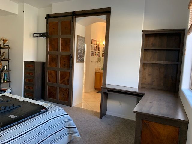 A bedroom with a sliding barn door leading to a bathroom