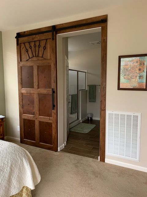 A bedroom with a sliding barn door leading to a bathroom