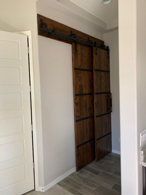 A hallway with a sliding barn door between two white doors