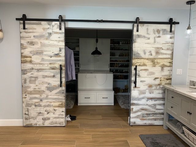 A bathroom with sliding barn doors leading to a closet