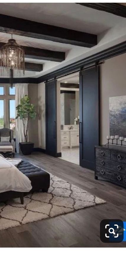 A bedroom with a bed, dresser, rug, and sliding barn doors