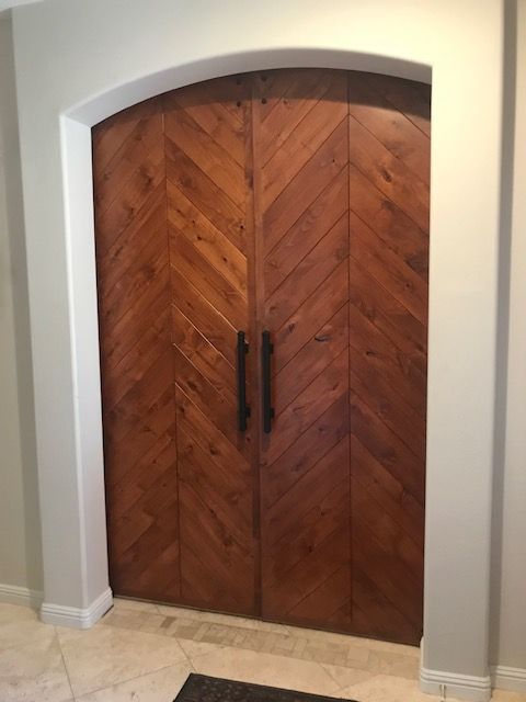 A wooden door with a herringbone pattern is in a room