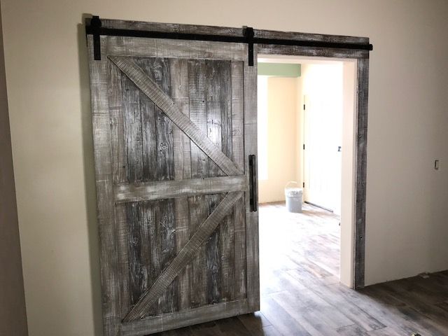 A sliding barn door is open to a room in a house