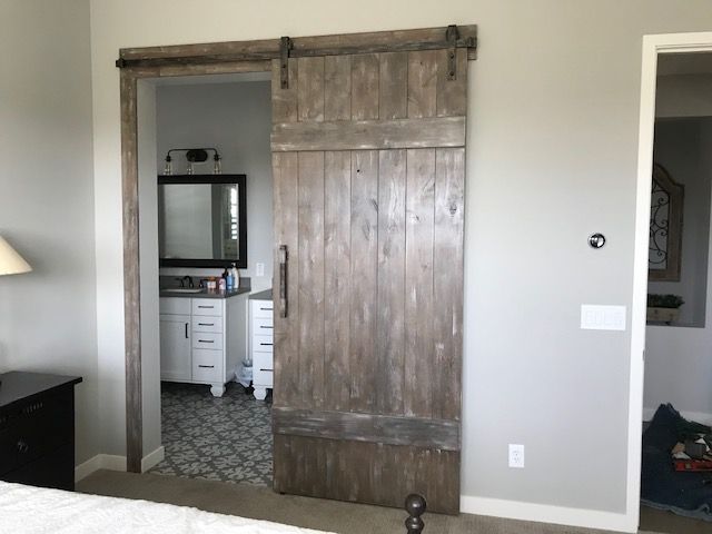 A bedroom with a sliding barn door leading to a bathroom