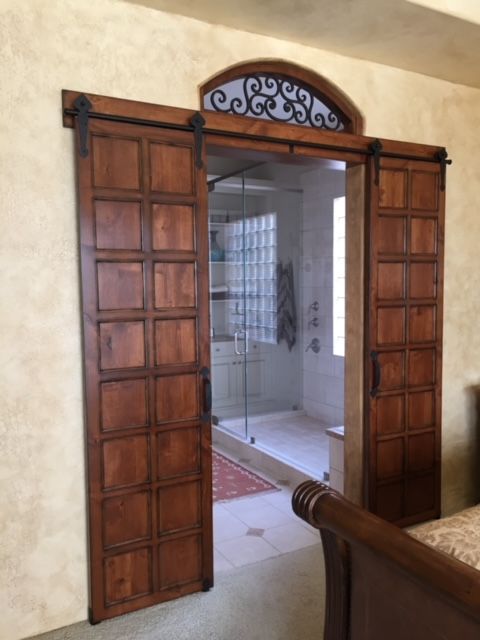 A bedroom with sliding barn doors leading to a bathroom