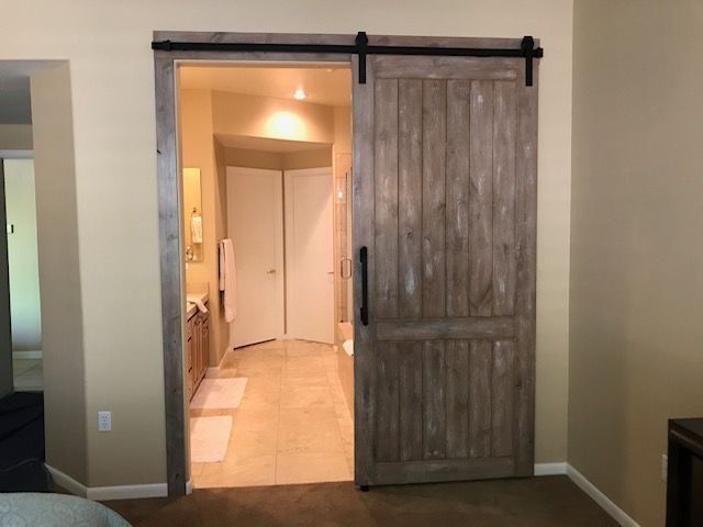 A bedroom with a sliding barn door leading to a bathroom