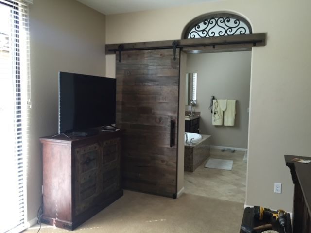 A bedroom with a sliding barn door leading to a bathroom
