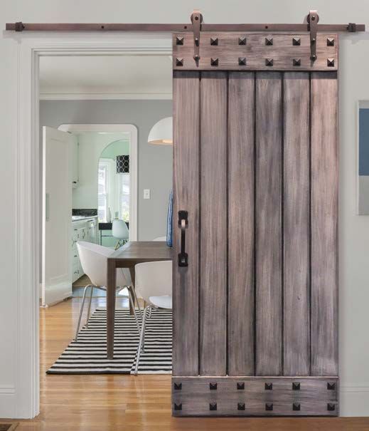 A sliding barn door is open to a dining room with a table and chairs