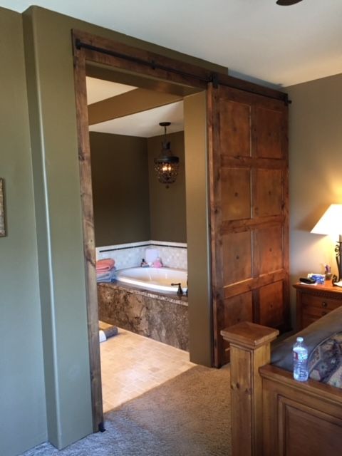 A bedroom with a sliding barn door leading to a bathroom