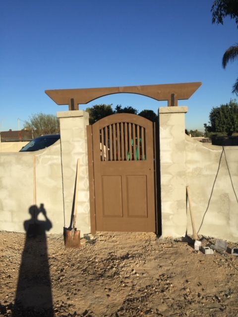 A recently constructed brick wall, complete with a wooden gate
