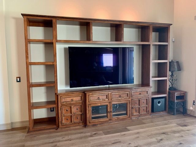 A living room with a wooden entertainment center and a flat screen television