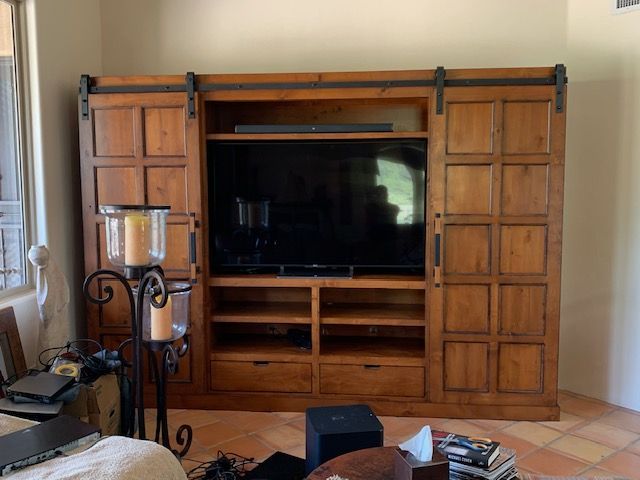 A living room with a wooden entertainment center and a flat screen television