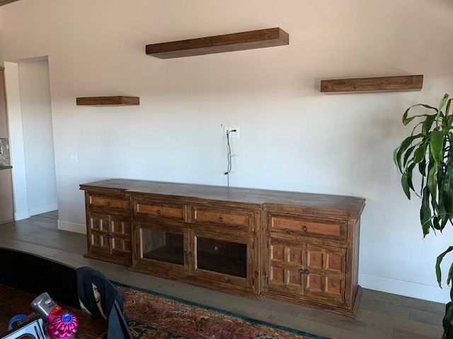 A living room with a wooden entertainment center and shelves