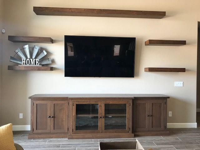 A living room with a flat screen television and wooden shelves