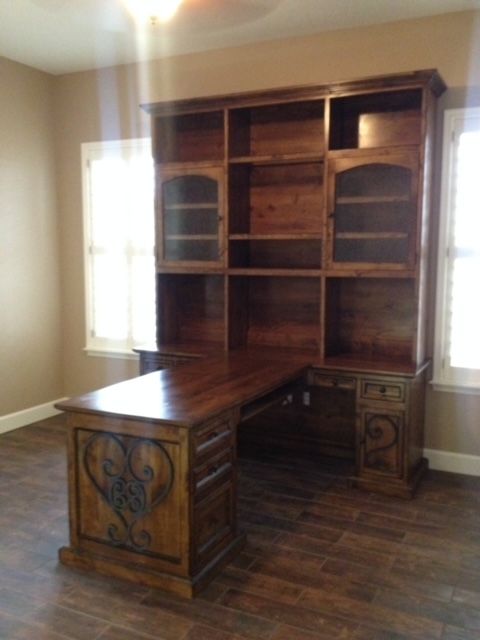 A home office room with a wooden desk and shelves