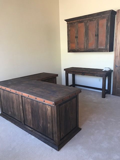 A home office room with a wooden desk and cabinets on the wall