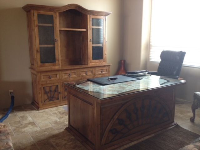 A wooden desk and chair in a home office room with a window