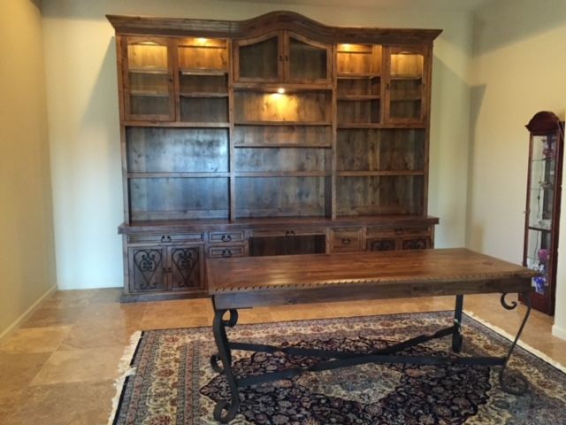 A home office room with a large wooden bookcase and a table
