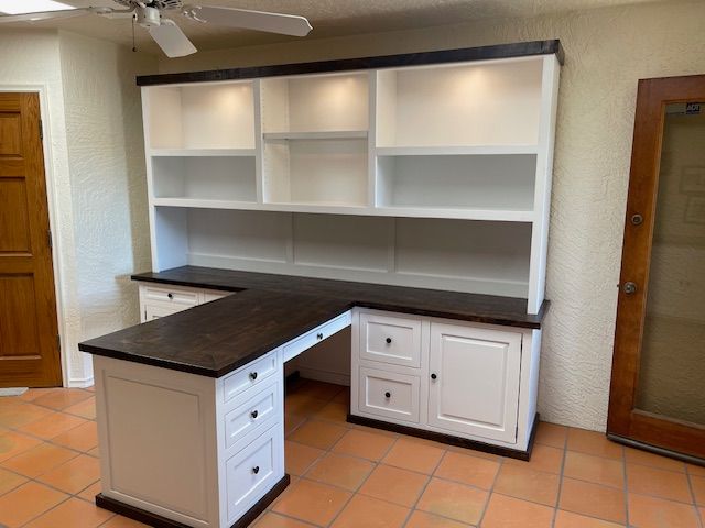 A home office room with a desk and shelves