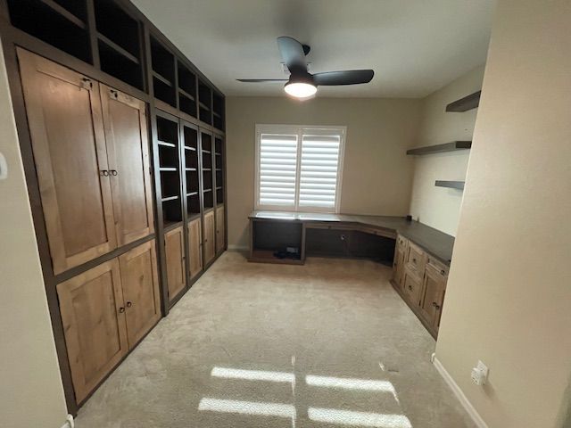 A home office room with lots of cabinets and a ceiling fan