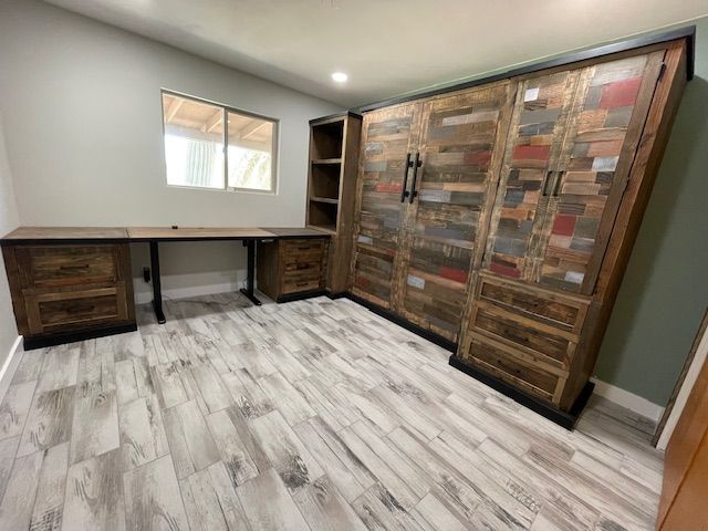 A home office room with a desk, cabinets, drawers, and a window