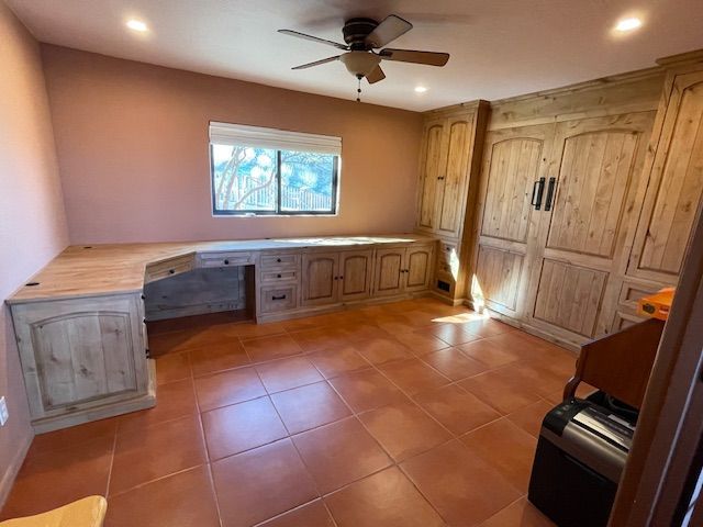 A home office room with a desk and a ceiling fan