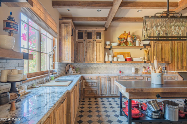 A kitchen with wooden cabinets, granite counter tops, and a stainless steel island