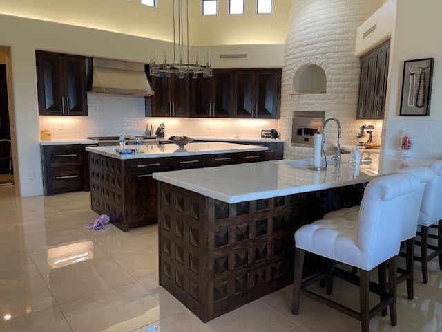 A kitchen with a large island, wooden cabinets, and white chairs
