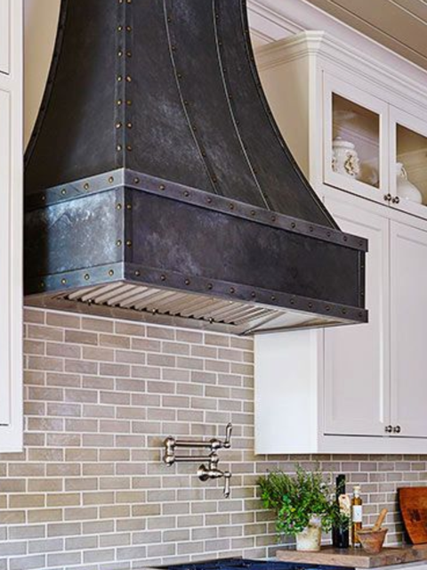 A kitchen with white cabinets and a black hood above the stove