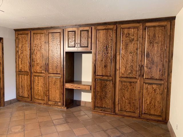 A kitchen in the process of being renovated, featuring numerous wooden cabinets and a tiled floor