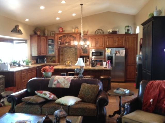 A living room with a couch and chairs and a kitchen in the background
