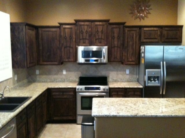 A kitchen with stainless steel appliances, wooden cabinets, and granite counter tops