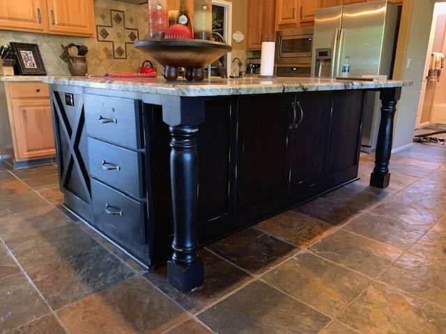 A kitchen with black cabinets and a large island in the middle