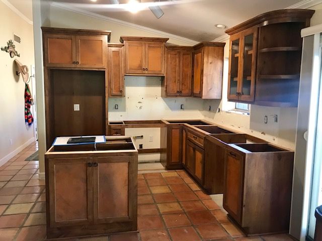 A kitchen with wooden cabinets and a tiled floor