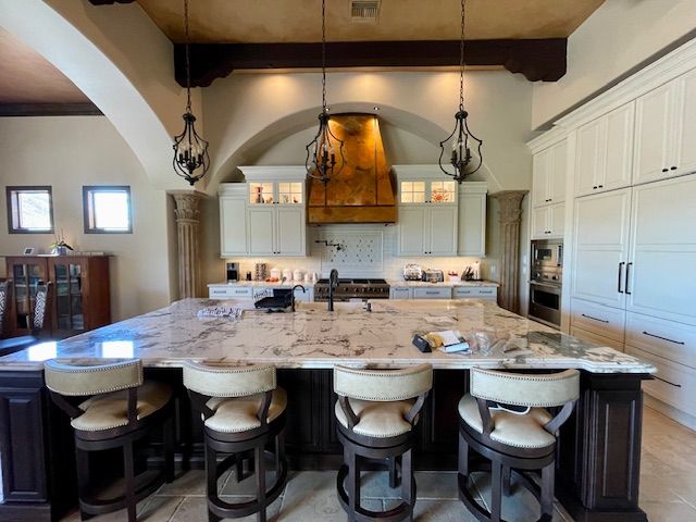 A kitchen with a large island, white cabinets, and stools