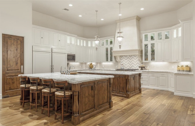 A large kitchen with a large island in the middle surrounded by wooden cabinets