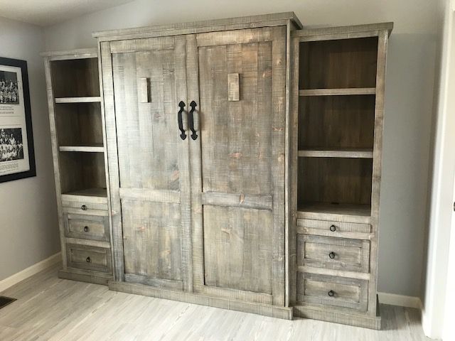 A large wooden Murphy bed with drawers and shelves in a room