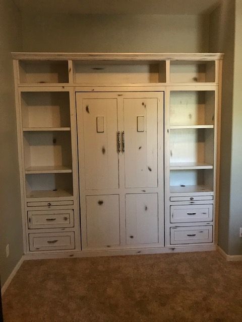 A large white Murphy bed with drawers and shelves in a room