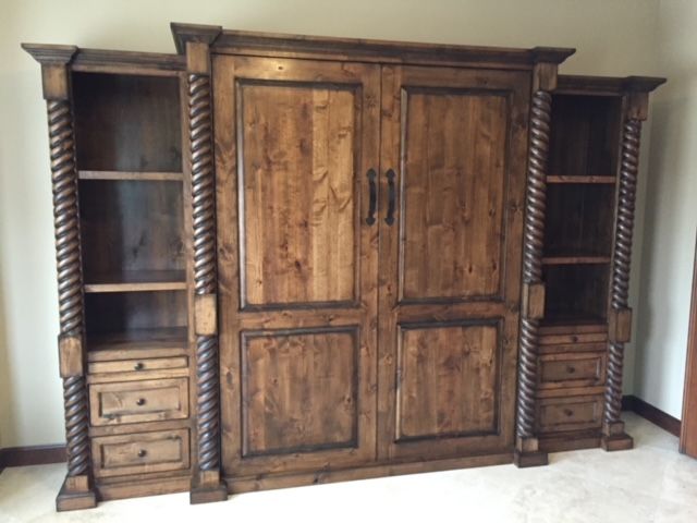 A large wooden Murphy bed with drawers and shelves in a room