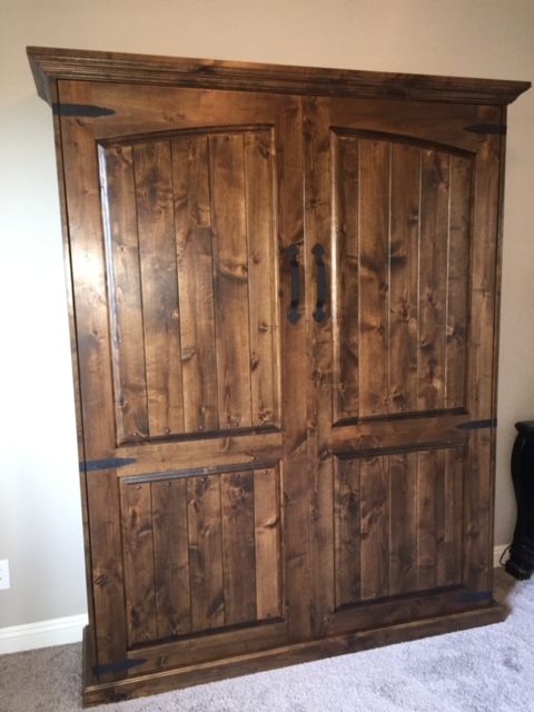 A large wooden Murphy bed is sitting in a room