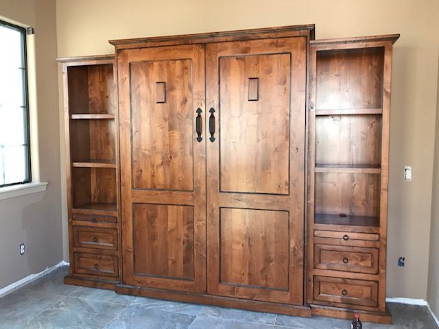 A large wooden Murphy bed with drawers and shelves in a room