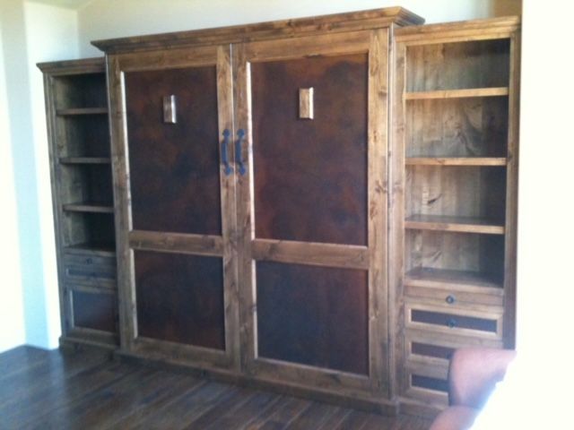 A large wooden Murphy bed with shelves and drawers in a room