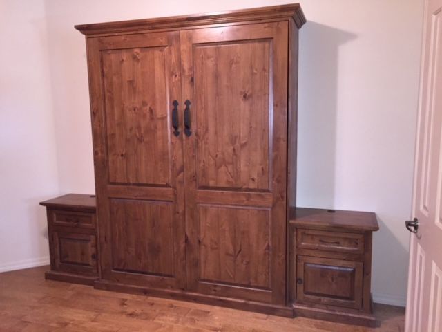 A wooden Murphy bed is sitting in a room next to an open door