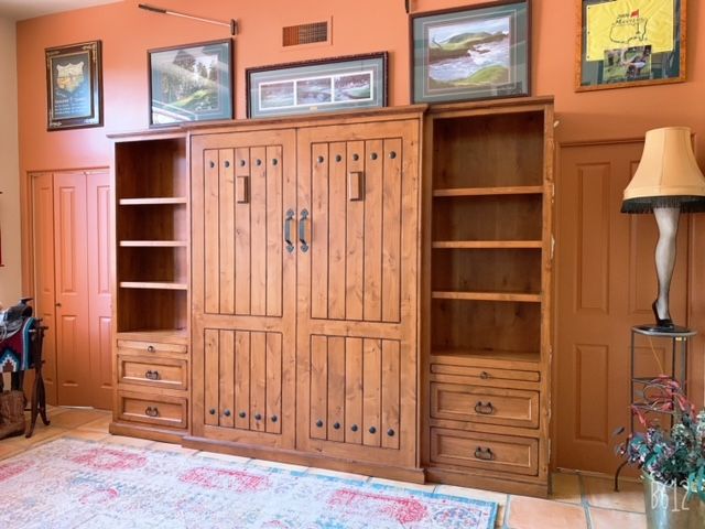 A large wooden Murphy bed with shelves and drawers in a room