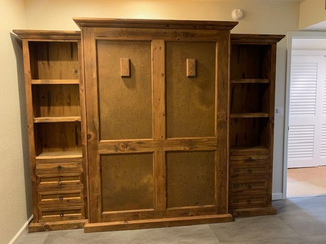 A large wooden Murphy bed with shelves and drawers in a room