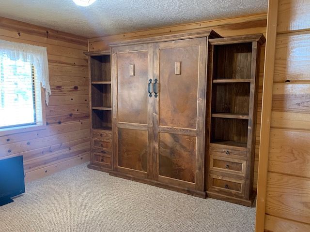 A bedroom with a wooden Murphy bed and shelves
