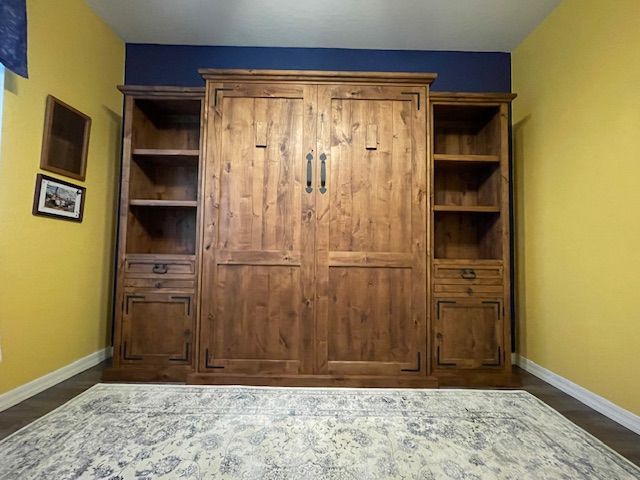 A room with a wooden Murphy bed and a rug