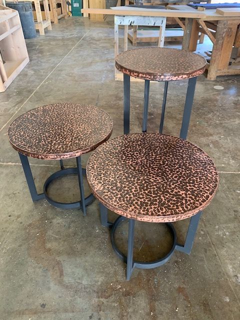 Three copper tables are sitting on a concrete floor